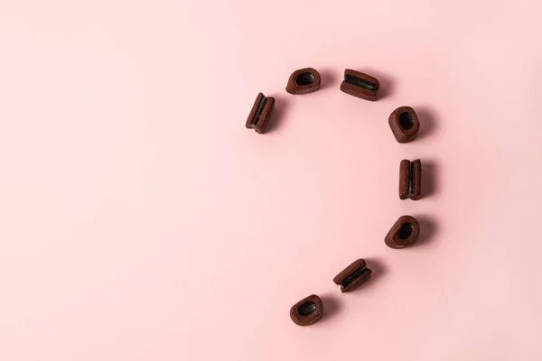 Pembe Pastel Arka Planda Yarım Kalp Meyan Kökü Kahverengi Şekerler — Stok fotoğraf