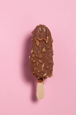 Pembe arka planda çikolata ve bademle kaplı dondurma.