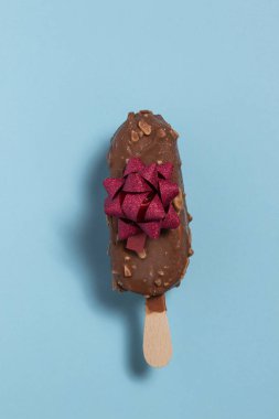 Çikolata kaplı dondurma ve mavi arka planda kırmızı fiyonklu badem.