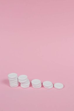 Renkli tabletler, pastel pembe arka plana istiflenir.