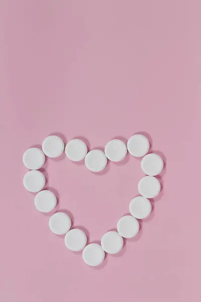 Effervescent tablets in the shape of a heart on a pink background