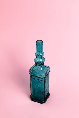 Pembe arka planda mavi kare cam şişe.