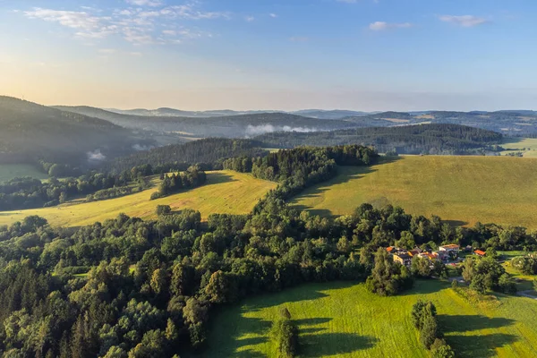 stock image Rural landscape of the Bohemian Forest, Czech: Sumava, Czech Republic. Green meadows and coniferous forests on a sunny morning. Aerial view from drone.