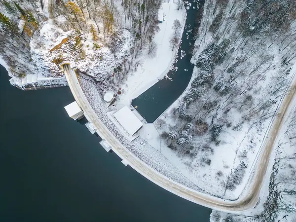 Sec water reservoir with concrete dam and wintertime snowy hills of Iron Mountains around. Czechia. Aerial view from drone.
