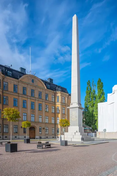 Slottsbacken의 오벨리스크는 스톡홀름의 하늘을 있으며 역사적인 건물은 측면과 나무를 둘러싸고 — 스톡 사진