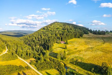 Bukovec Mountain rises above Jizerka village, showcasing lush greenery and scenic views under a bright, clear sky, with paths and a winding stream visible. clipart