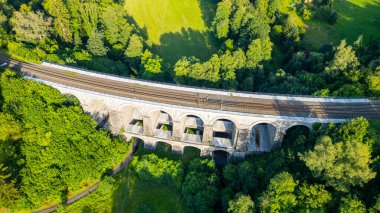 Aerial view of the Sychrov Railway Bridge showcasing its arches above lush greenery, highlighting the natural landscape in Czechia. clipart