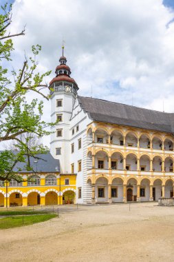 Charming courtyard of Velke Losiny Chateau in Czechia, surrounded by historic architecture and green trees under a partly cloudy sky on a pleasant day. clipart