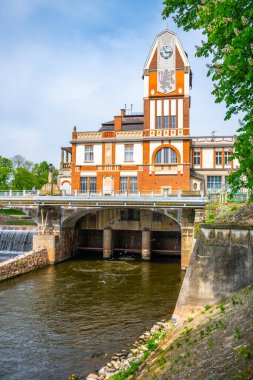 The hydroelectric power station Hucak showcases its Art Nouveau architecture in Hradec Kralove, Czechia, as water flows beneath its bridge on a clear day. A blend of nature and historic engineering. clipart