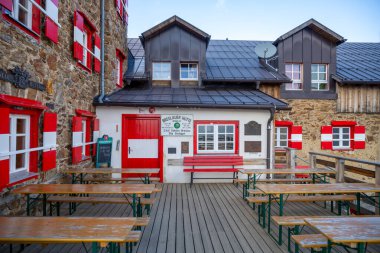 The Breslauer Hut at Wildspitze offers a cozy retreat with rustic charm, showcasing wooden seating and vibrant red accents clipart