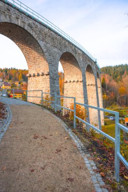 On a bright autumn day, the Smrzovka railway viaduct stands majestically in the Jizera Mountains, surrounded by vibrant foliage and scenic landscapes, inviting exploration and admiration. clipart