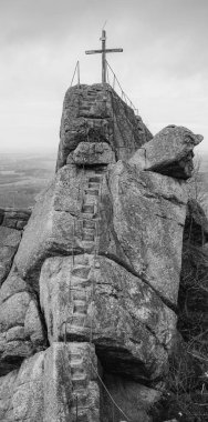 A wooden summit cross stands atop the Oresnik granite formation in Hejnice, Jizera Mountains, offering stunning views of the surrounding landscape and a unique hiking experience. clipart