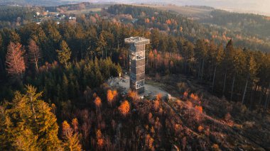 The wooden lookout tower at Cisarsky Kamen near Liberec offers stunning views during an autumn sunset, with colorful foliage and serene forest surroundings creating a peaceful atmosphere. clipart