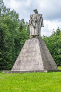 The statue of Jan Zizka stands majestically on a pyramid-shaped pedestal in Trocnov, sheltered by lush greenery, honoring the Hussite leaders legacy and birthplace. clipart