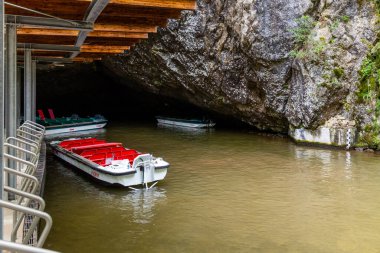 Tourist boats await visitors at the entrance of Punkva Caves in Moravian Karst. The serene waters reflect the striking cave formations, inviting exploration and adventure. clipart