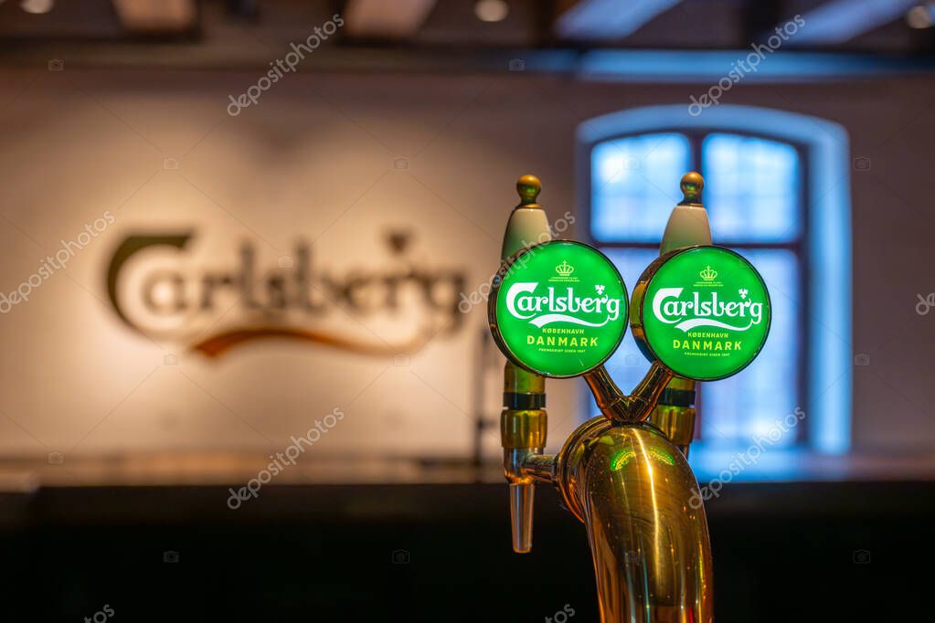 COPENHAGEN, DENMARK - APRIL 11, 2025: Carlsberg Brewery elegant beer tap features green illuminated displays indicating options. It is situated in a lively bar setting, creating a warm atmosphere