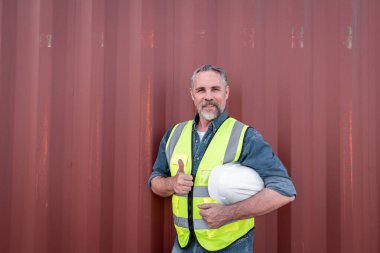 Engineers wearing safe uniform with radio communication working in the construction container dock yard checking and inspection containers data is container shipping Logistics business concept.