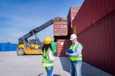 Engineers wearing safe uniform with radio communication working in the construction container dock yard checking and inspection containers data is container shipping Logistics business concept.