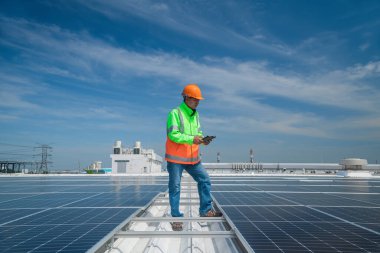 Çatıda yürüyen mühendisler ekipman kutusu ve telsiz iletişimiyle güneş hücresi panelini inceler ve kontrol ederler. Güneş pili akıllı ızgara ekolojik enerji alternatif enerji güneş ışığı enerji fabrikası konseptidir.