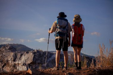 Yürüyüşçüler ya da gezginler sırt çantası taşıyan gezginler, yürüyüş direkleri uzak mesafeye bakar ve muhtemelen gezi ve tatil eko-turizmi konseptine rehberlik ederler..