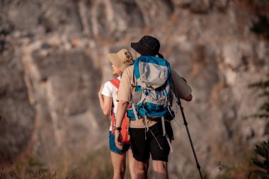 Gezginler ya da gezginler sırt çantası taşıyan gezginler, yürüyüş direkleri uzak mesafeye bakar ve muhtemelen yürüyüş ve yol keşfi ve tatil eko-turizmi kavramına rehberlik ederler..