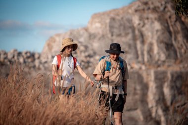 Gezginler ya da gezginler sırt çantası taşıyan gezginler, yürüyüş direkleri uzak mesafeye bakar ve muhtemelen yürüyüş ve yol keşfi ve tatil eko-turizmi kavramına rehberlik ederler..