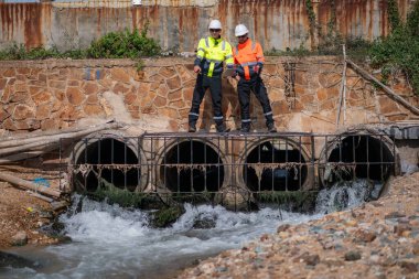 Çevre mühendisi veya işçiler, sistemlerin etkin çevre düzenlemelerini sağlamak için büyük bir endüstriyel atık su veya kirlilik izleme ve bakımı boyunca atık suyu inceleyen işçiler.