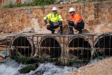 Çevre mühendisi veya işçiler, sistemlerin etkin çevre düzenlemelerini sağlamak için büyük bir endüstriyel atık su veya kirlilik izleme ve bakımı boyunca atık suyu inceleyen işçiler.