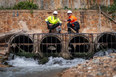 Çevre mühendisi veya işçiler, sistemlerin etkin çevre düzenlemelerini sağlamak için büyük bir endüstriyel atık su veya kirlilik izleme ve bakımı boyunca atık suyu inceleyen işçiler.