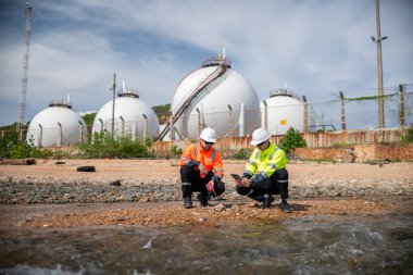 Çevre mühendisi veya işçiler, sistemlerin etkin çevre düzenlemelerini sağlamak için büyük bir endüstriyel atık su veya kirlilik izleme ve bakımı boyunca atık suyu inceleyen işçiler.