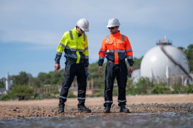 Çevre mühendisi veya işçiler, sistemlerin etkin çevre düzenlemelerini sağlamak için büyük bir endüstriyel atık su veya kirlilik izleme ve bakımı boyunca atık suyu inceleyen işçiler.