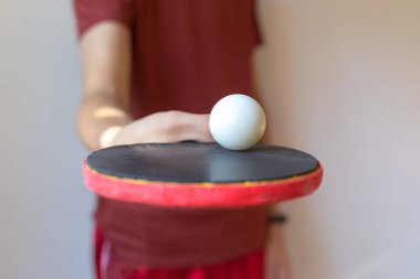 Beyaz arka planda izole edilmiş pinpon raketi olan bir adamın eli. Masa tenisi raketi olan bir genç. Spor konsepti.