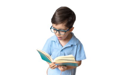 Portrait of boy in glasses with book. Remote learning. Distance education. Homework. Treat lazy eye, amblyopia, strabismus. Boy is reading. Education concept. clipart