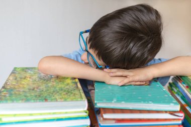 Mutlu şirin çocuk kitapların üzerinde uyuyor, öğrenmeyi seviyor. Amblyopia, strabismus. Öğrenme kavramı.