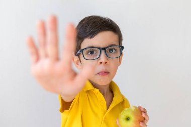 Beyaz tenli, gözlüklü, sevimli çocuk dur işareti yapıyor. Beyaz stüdyo arka planında el izolasyonu var. Yaklaş. Hayır de, kaprisler, çocuk duyguları ve yüz ifadesi. Sağlıklı gıda konsepti