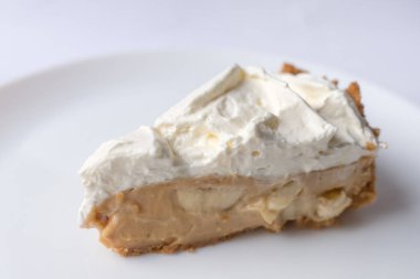 Beyaz arka planda karamel soslu ve peynirli banoffee muzlu turta. Geleneksel İngiliz pastası. Yemek hazır. Yemek pişirme konsepti.