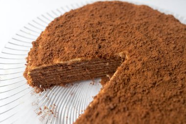 Beyaz arka planda kakao tozu olan ballı pasta. Medovik Spartak çikolatalı pasta. Yemek hazır. Yemek pişirme konsepti.