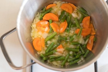 Mutfaktaki ocağın tavasında sebze çorbası var. Yemek vakti..