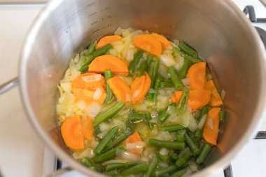 Mutfaktaki ocağın tavasında sebze çorbası var. Yemek vakti..