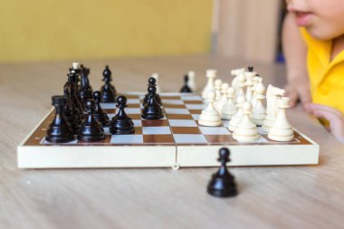 Gözlüklü sevimli çocuk satranç tahtasındaki satranç taşlarını gösteriyor. Çocuk eğitimi ve gelişimi. Çocuklar için satranç oyunu.