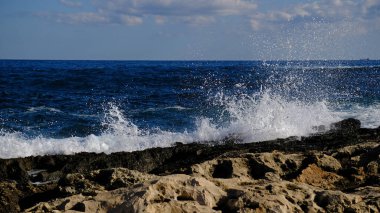 Mavi deniz dalgası, beyaz köpük ve su sıçraması. Malta adasında taş plaj, kumlu plaj yok. Yaz tatili sınır çerçevesi konsepti. Tropik ada tatili arka planı. Turist seyahat afişi tasarım şablonu.
