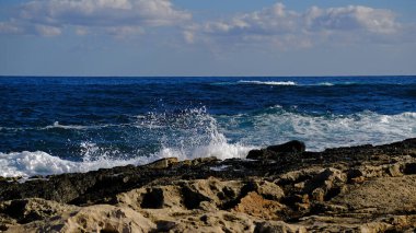 Mavi deniz dalgası, beyaz köpük ve su sıçraması. Malta adasında taş plaj, kumlu plaj yok. Yaz tatili sınır çerçevesi konsepti. Tropik ada tatili arka planı. Turist seyahat afişi tasarım şablonu.