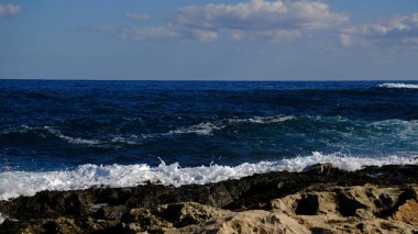 Mavi deniz dalgası, beyaz köpük ve su sıçraması. Malta adasında taş plaj, kumlu plaj yok. Yaz tatili sınır çerçevesi konsepti. Tropik ada tatili arka planı. Turist seyahat afişi tasarım şablonu.