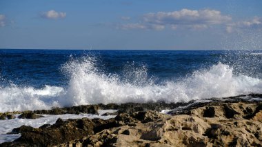 Mavi deniz dalgası, beyaz köpük ve su sıçraması. Malta adasında taş plaj, kumlu plaj yok. Yaz tatili sınır çerçevesi konsepti. Tropik ada tatili arka planı. Turist seyahat afişi tasarım şablonu.