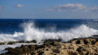 Mavi deniz dalgası, beyaz köpük ve su sıçraması. Malta adasında taş plaj, kumlu plaj yok. Yaz tatili sınır çerçevesi konsepti. Tropik ada tatili arka planı. Turist seyahat afişi tasarım şablonu.