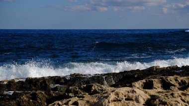 Mavi deniz dalgası, beyaz köpük ve su sıçraması. Malta adasında taş plaj, kumlu plaj yok. Yaz tatili sınır çerçevesi konsepti. Tropik ada tatili arka planı. Turist seyahat afişi tasarım şablonu.