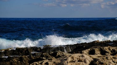 Mavi deniz dalgası, beyaz köpük ve su sıçraması. Malta adasında taş plaj, kumlu plaj yok. Yaz tatili sınır çerçevesi konsepti. Tropik ada tatili arka planı. Turist seyahat afişi tasarım şablonu.