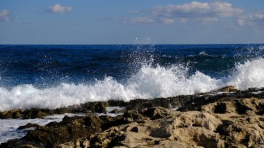 Mavi deniz dalgası, beyaz köpük ve su sıçraması. Malta adasında taş plaj, kumlu plaj yok. Yaz tatili sınır çerçevesi konsepti. Tropik ada tatili arka planı. Turist seyahat afişi tasarım şablonu.
