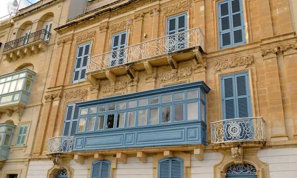 stock image Exterior of typical houses on the Mediterranean island of Malta. Typical residential houses in the cities in Malta, multiple floors and colorful wooden balconies and beautiful limestone buildings.