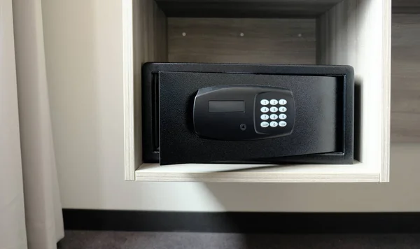 Metal safe box in the closet. Small narrow safe for keeping money or valuables in the hotel. Open safe door with buttons for entering a password. Compact strongbox inside cabinet. Empty safe.